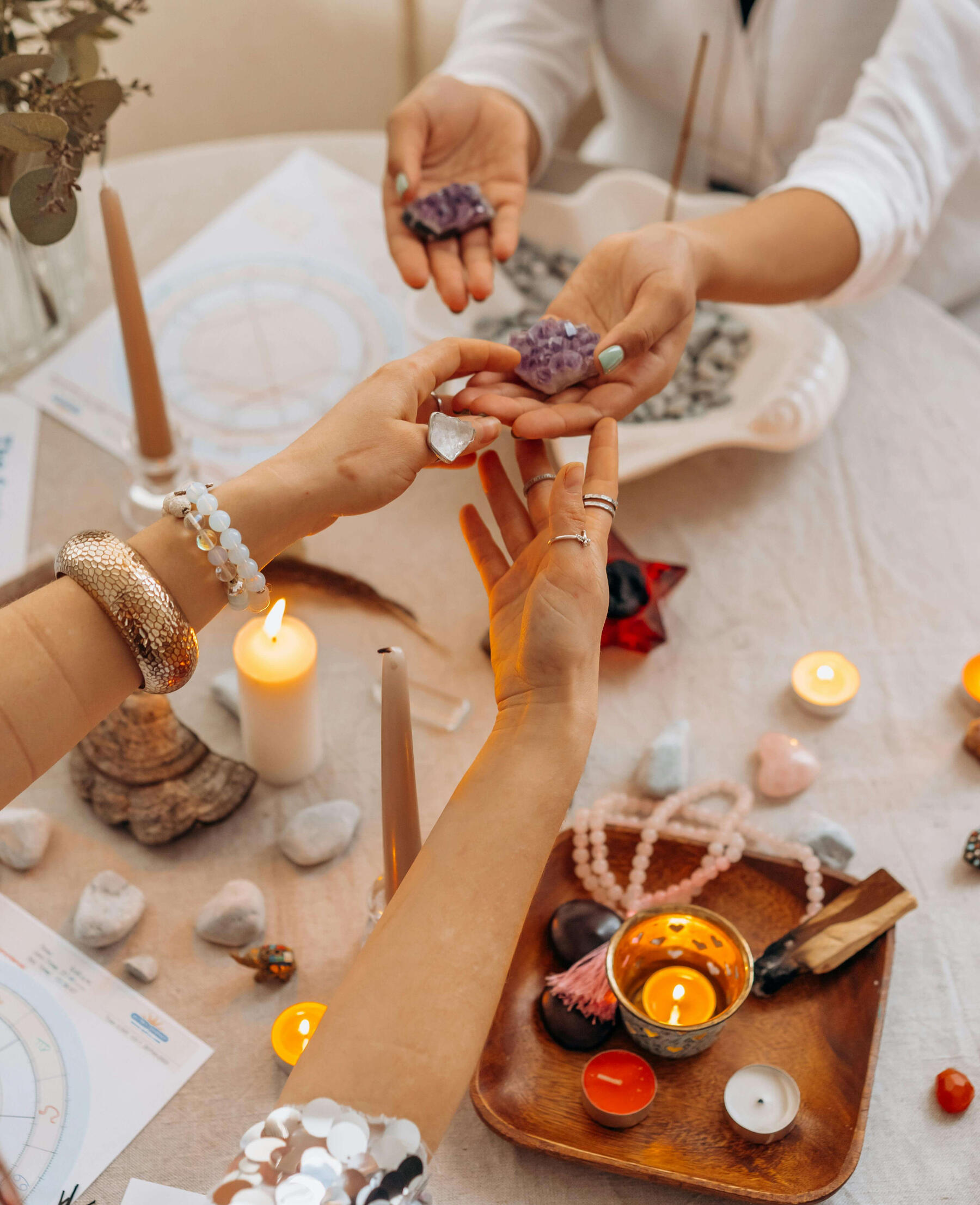 Photo of two women holding crystals at a table with many crystals, cancles and mala beads.